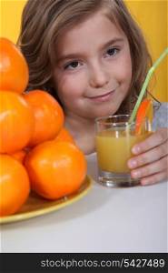 a little blonde girl drinking orange juice