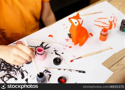 a little boy paints a toy fox made of clay. DIY concept.. a little boy paints a toy fox made of clay. DIY concept