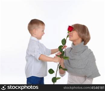 a little boy presenting his mother a red rose