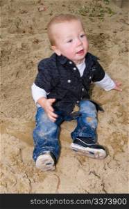 a little boy sitting n the sandbox