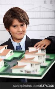 a little boy wearing suit and tie behind a district model