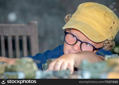 a little boy with a yellow cap plays with toys outside