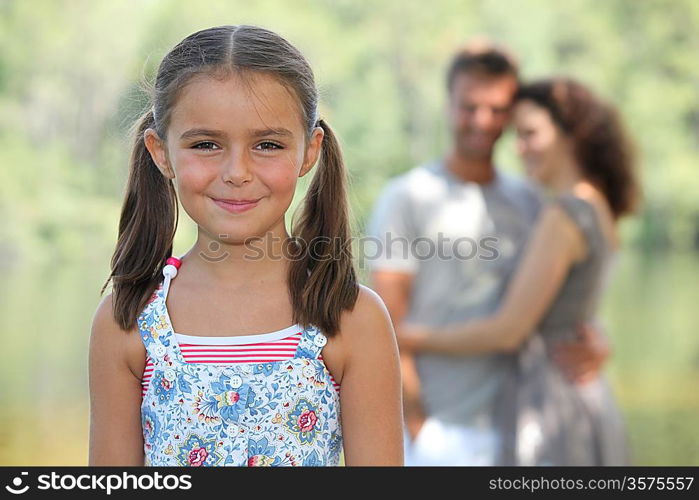 A little girl and her parents in a park.