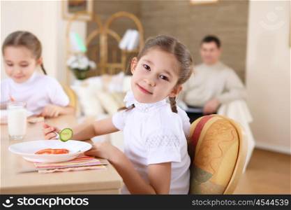 a little girl at home having meal and her family on the background