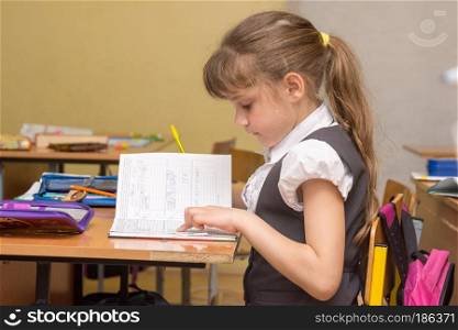 A little girl in a class carefully reads a diary entry