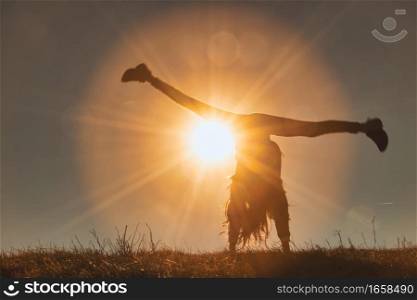 A little girl performs the wheel with the sun behind