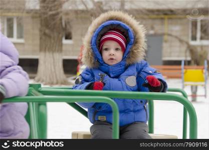 A little girl riding a little merry-go-round on the Playground. The girl is afraid of.