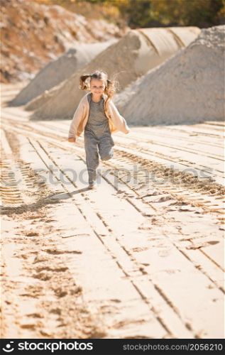 A little girl runs happily among the sand.. A girl against the background of sand and sky 3335.