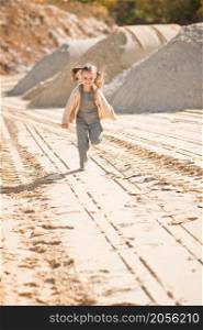 A little girl runs happily among the sand.. A girl against the background of sand and sky 3335.
