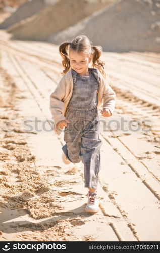 A little girl runs happily among the sand.. A girl against the background of sand and sky 3336.