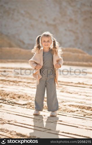 A little girl runs happily among the sand.. A girl against the background of sand and sky 3338.
