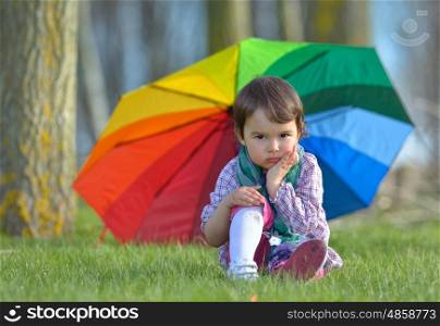 A little girl with a rainbow umbrella in forest