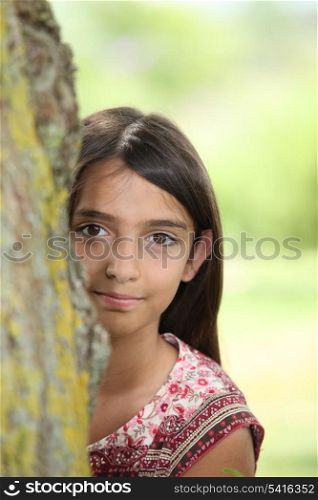 A little Latina hiding behind a tree.