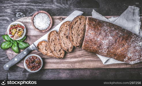 A loaf of ciabatta with antipasti and basil