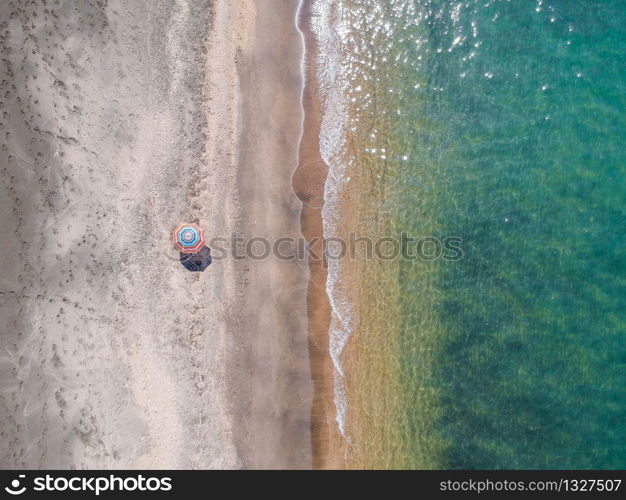 A lone beach umbrella on the sand beach, flat aerial view for background