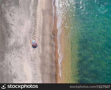 A lone beach umbrella on the sand beach, flat aerial view for background