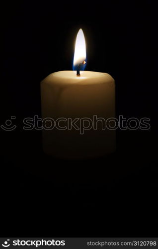 A lone candle provides light in a darkened room