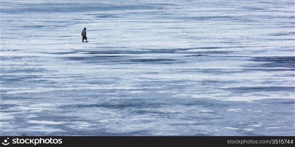 a lone fisherman is on the ice of winter river