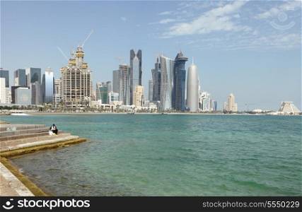 A lone fisherman tries his luck on the doha corniche in Qatar with the bulk of the city&rsquo;s new high-rise skyline soaring above him