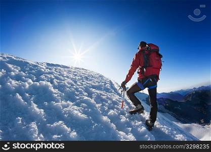 A lone mountaineer reach the top of a high mountain peak. Monte Rosa, Swiss.