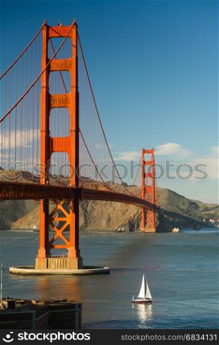 A lone sailboat passes under the Golden Gate Bridge in San Francisco