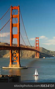A lone sailboat passes under the Golden Gate Bridge in San Francisco