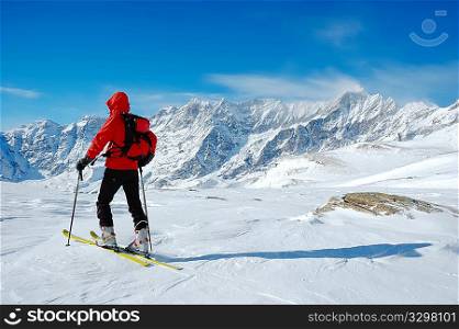 A lonely backcountry skier in a sunny winter day, alpine scenic, horizontal orientation