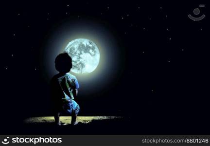 A lonely boy sitting alone looking at the moon in the night sky with the stars at night.