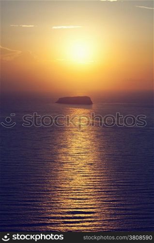 A lonely island, rock on the sea at sunset. Santorini, Greece.