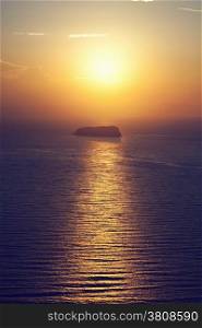 A lonely island, rock on the sea at sunset. Santorini, Greece.