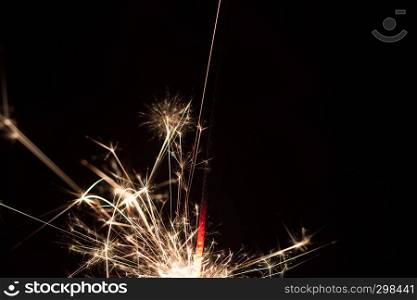 A long exposure close-up shot of a burning sparkler at night.