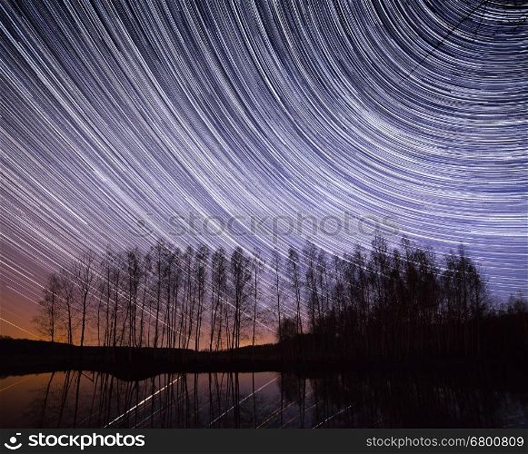 A long exposure of the sky over a lake with the star trails