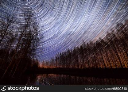 A long exposure of the sky over a lake with the star trails