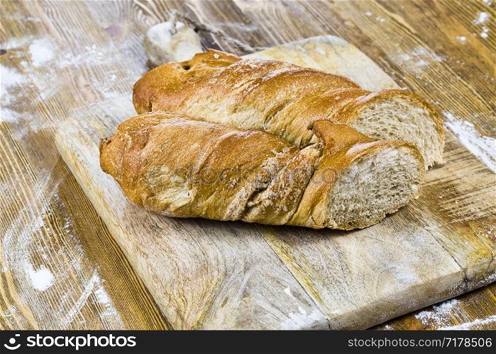 a long loaf of wheat bread cut into even pieces and pieces while cooking in the kitchen area. a long loaf of wheat bread
