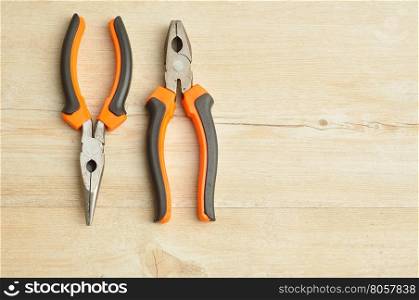 A long nose pliers and a pliers isolated on a wooden background