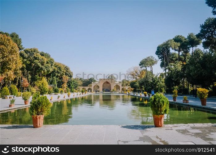 A long pool in front of the ancient Chehel Sotoun palace surrounded by trees in the garden. Isfahan, Iran.