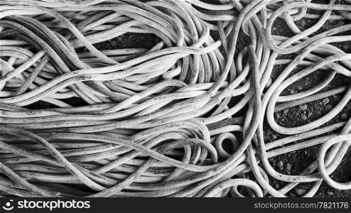 A long rope is roughly coiled on the ground into a tangled mess