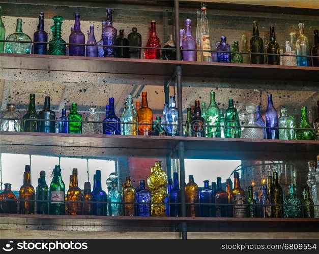 A lot of different colored glass bottles on shelves.
