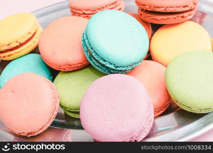 A lot of french colorful macarons on a pink background