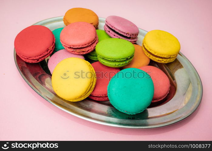 A lot of french colorful macarons on a pink background