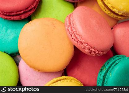 A lot of french colorful macarons on a pink background