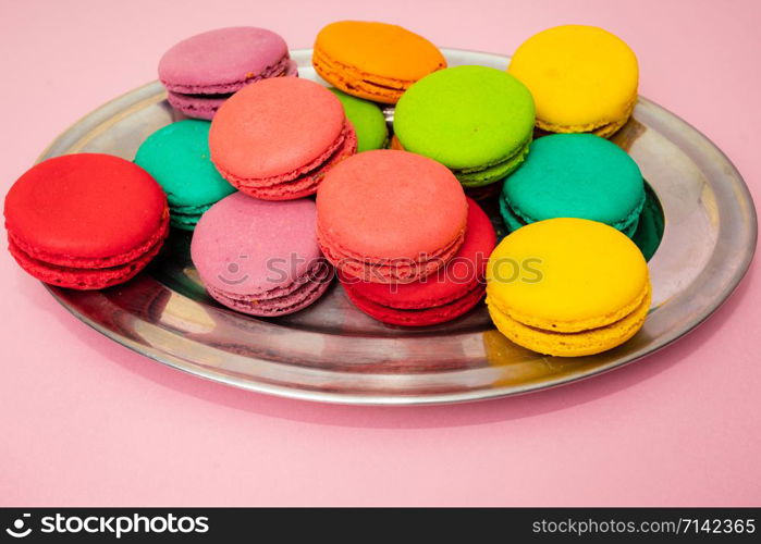 A lot of french colorful macarons on a pink background