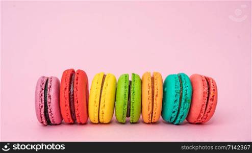 A lot of french colorful macarons on a pink background