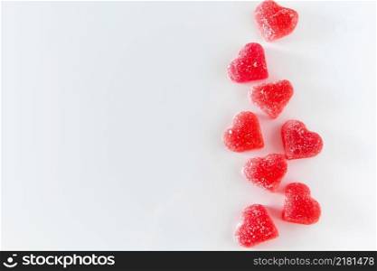 A lot of red heart-shaped marmalade on a white background. Place for your text.. Red heart-shaped marmalade on a white background.