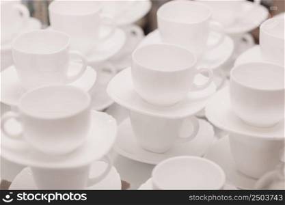 a lot of rows of pure white cups with plates for coffee or tea break . High quality photo.. a lot of rows of pure white cups with plates for coffee or tea break . High quality photo