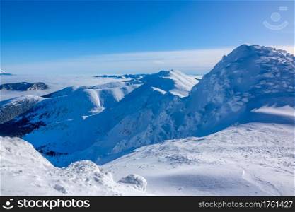 A lot of snow on the peaks and slopes of the winter mountains. Sunny weather and cloudless blue sky. Blue Sky over Snowy Peaks
