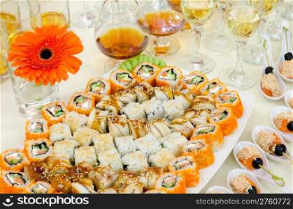 a lot of sushi and drinks on buffet table, catering