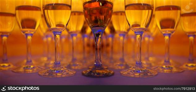A lot of wineglasses with champagne standing at the colorful background. Yellow, red and blue colors
