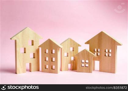 A lot of wooden houses on a pink background. The concept of the city or town. Investing in real estate, buying a house. Management and business management, market coverage. Construction of buildings.