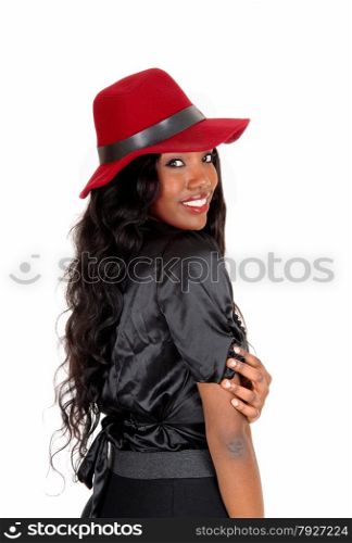 A lovely African American woman in a black blouse and long black curlyhair with a red hat, looking over her shoulder, isolated for white background.